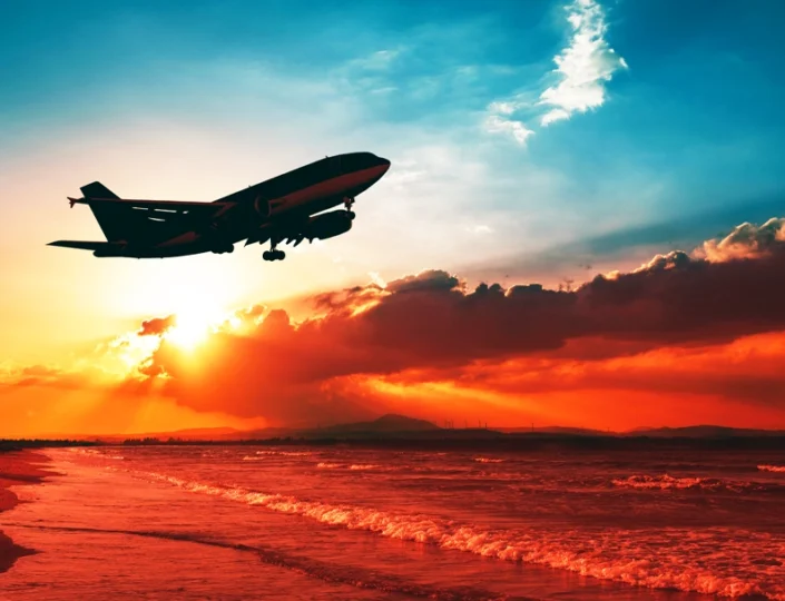 airplane taking off over shoreline beach during sunset