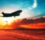 airplane taking off over shoreline beach during sunset