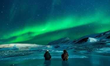 visit alaska aurora night sky with couple sitting on ice