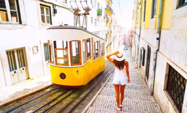 portugal woman walking beside building yellow tram in road